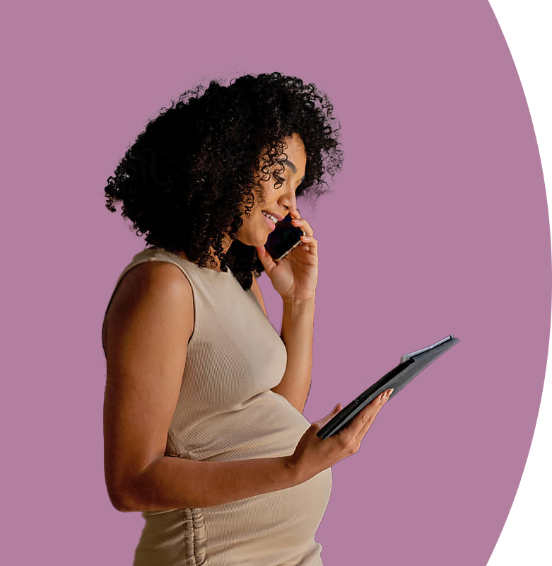 An expectant mother looks down at a tablet while speaking on the phone.
